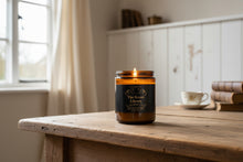 Load image into Gallery viewer, Candle in a jar labeled 'The Secret Library' on a wooden table with a window and books in the background. Karmen’s Candle Lights
